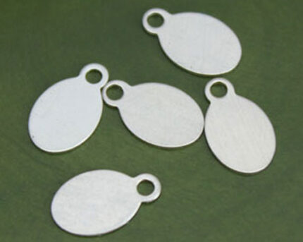 Blank oval metal pendants on green background