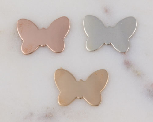Three metal butterfly-shaped charms on marble Three metal butterfly-shaped charms on marble