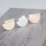 Three half-moon metallic stud earrings on slab