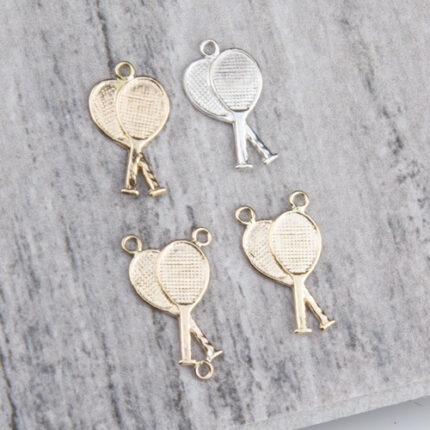 Four metallic tennis racket charms on gray background