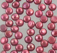 Scattered metallic pink beads on gray background