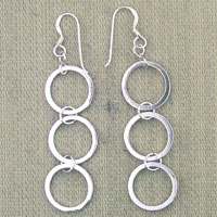 Silver triple hoop dangle earrings on beige fabric