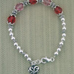 Silver bracelet with red beads and heart charm