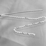 Silver chain threader earring on gray fabric
