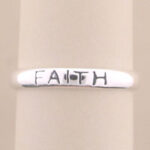Close-up of silver ring engraved with "FAITH