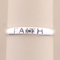 Close-up of silver ring engraved with "FAITH