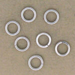 Seven silver metal jump rings on tan background