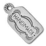 Silver stamped metal tag reading "HANDMADE