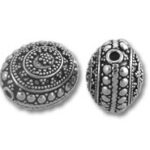 Two ornate silver beads with dotted spiral patterns