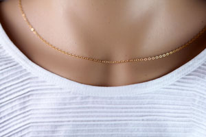 Neck with delicate gold chain necklace, white top