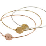 Three mixed-metal bangles with disc charms